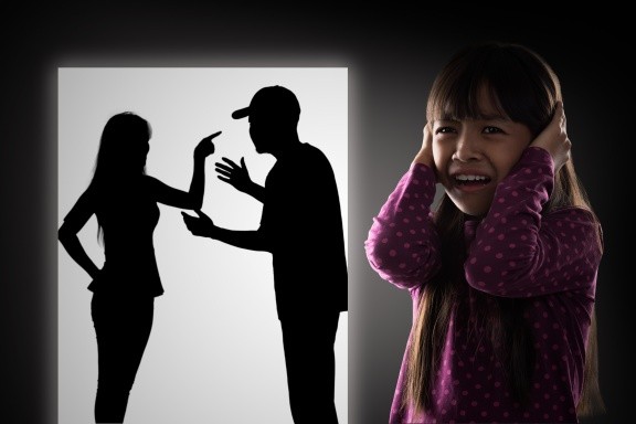 Crying illtle asian girl with her fighting parents in the background