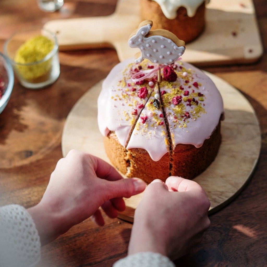 Person getting slice of brown cake with rabbit cookie on top