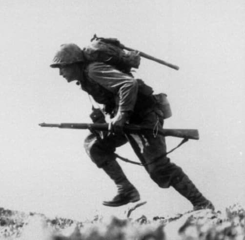 A soldier running while holding a rifle