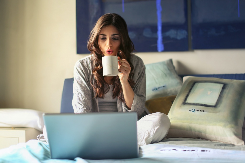 A woman drinking coffee and operating a computer