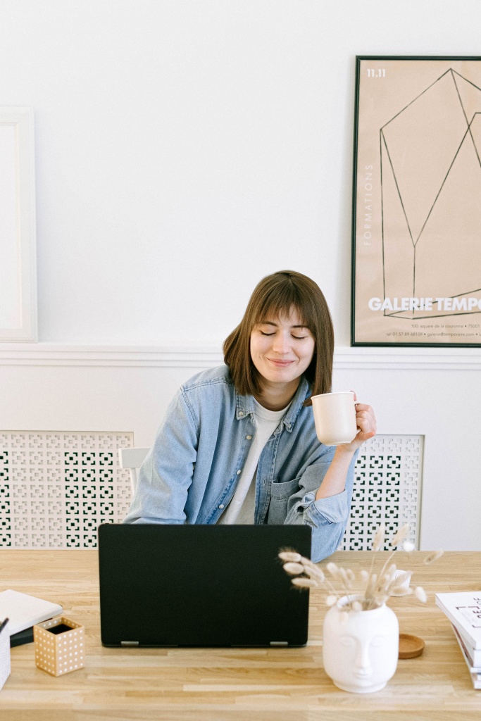 A lady drinking coffe and operating a laptop