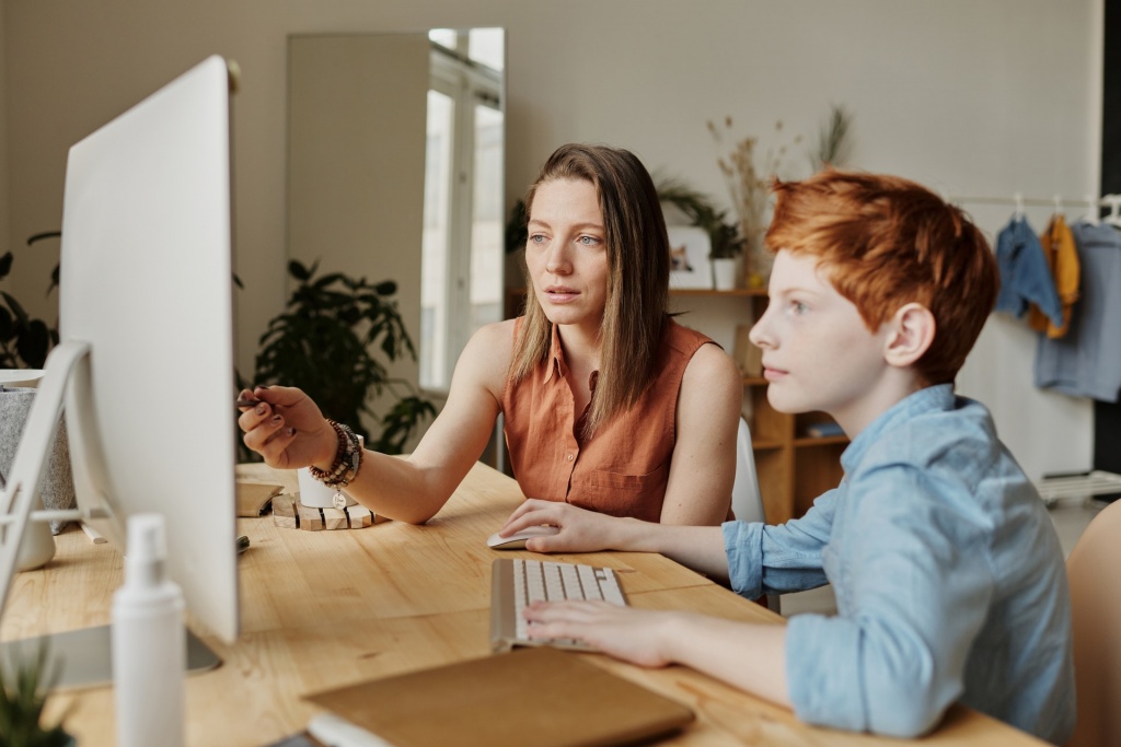 A woman  guiding her son for his online class