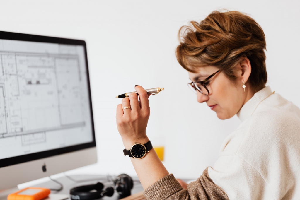 A woman holding a pen while sitting at a computer