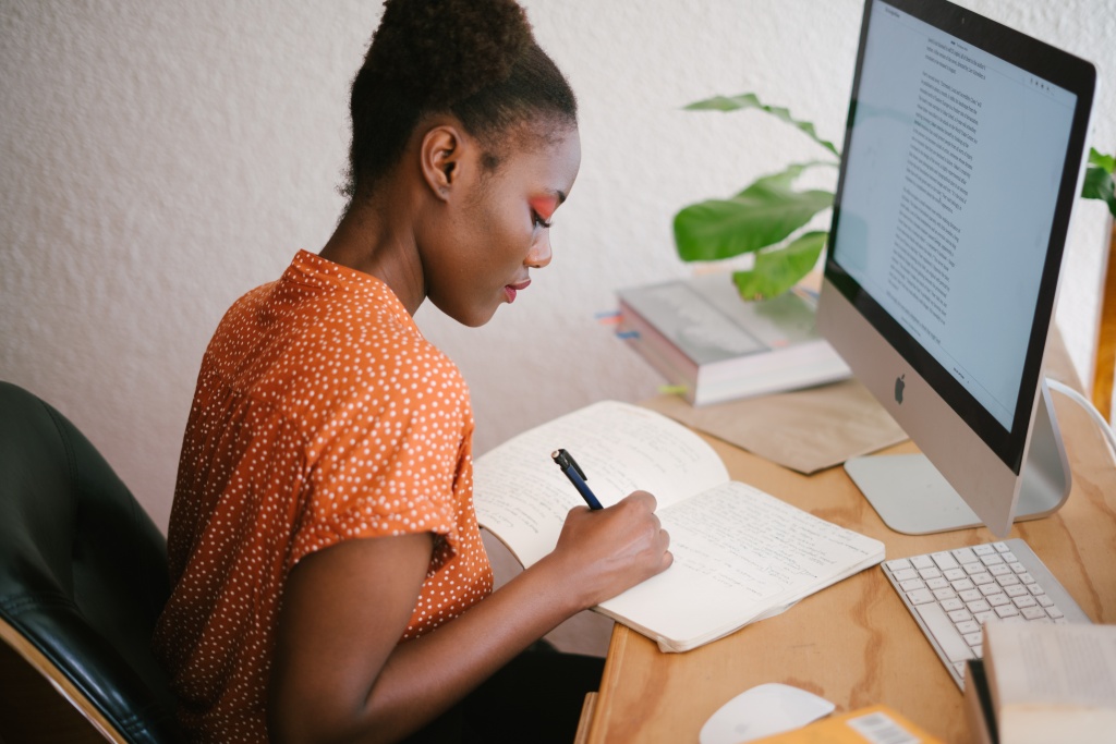 A woman working on her computer and writing