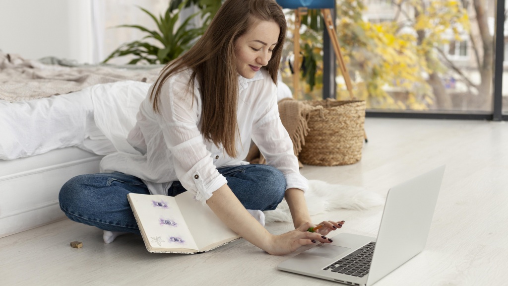 A woman sitting on the floor and operating a computer