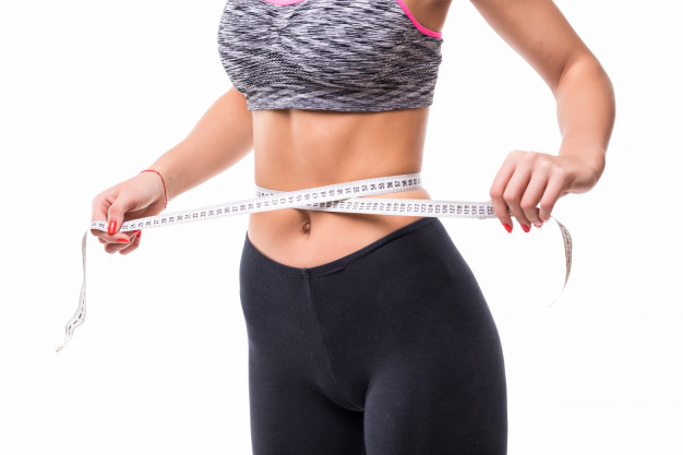 fitness woman measuring her body with ruler dressed in fashion sportswear losing weight