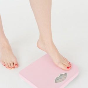 woman stepping on pink scale